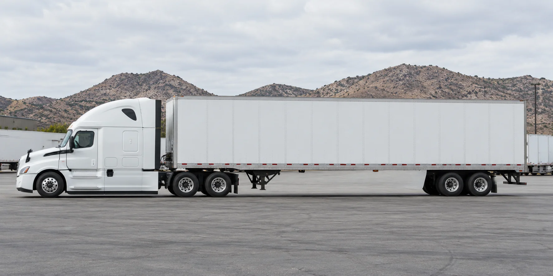 Illustrative white tractor-trailer at a California freight yard