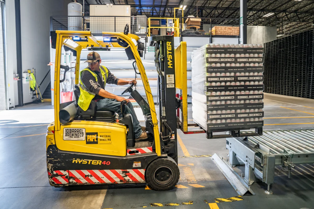 Warehouse forklift operator moving freight in an industrial storage area
